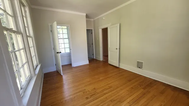 a view of an empty room with glass door and wooden floor