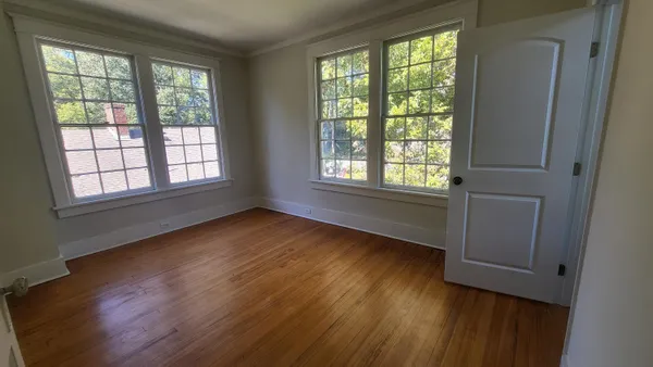 a view of an empty room with wooden floor and a window