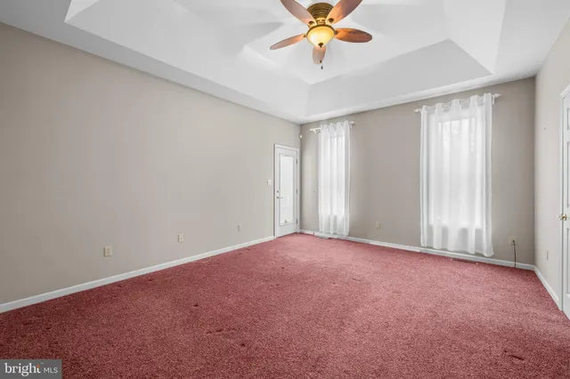 an empty room with a chandelier fan and windows