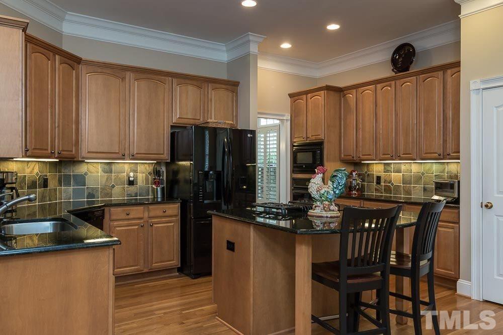 3920 Bentley Bridge Road Raleigh, NC 27612 - Photo 20 of 20 a kitchen with kitchen island granite countertop a table chairs microwave and refrigerator