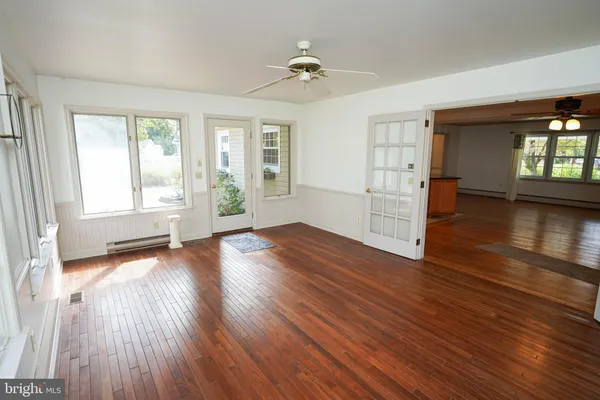 a view of empty room with wooden floor and fan