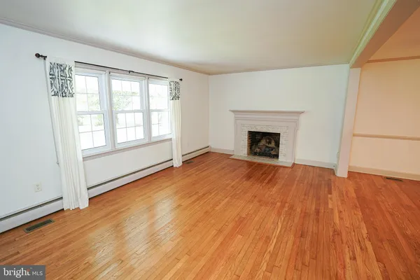 an empty room with wooden floor fireplace and windows