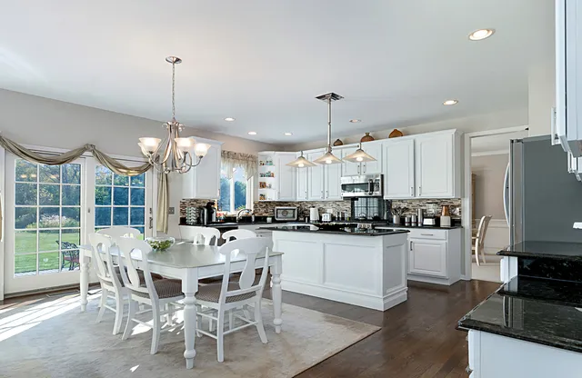 a kitchen with stainless steel appliances a dining table chairs stove and refrigerator