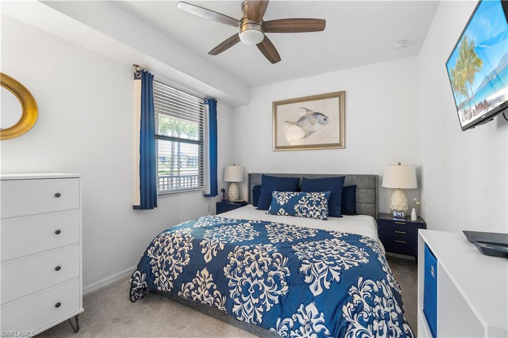 9820 Giaveno Circle, Unit 1422 Naples, FL 34113 - Photo 11 of 36 a bedroom with a large bed and a chandelier