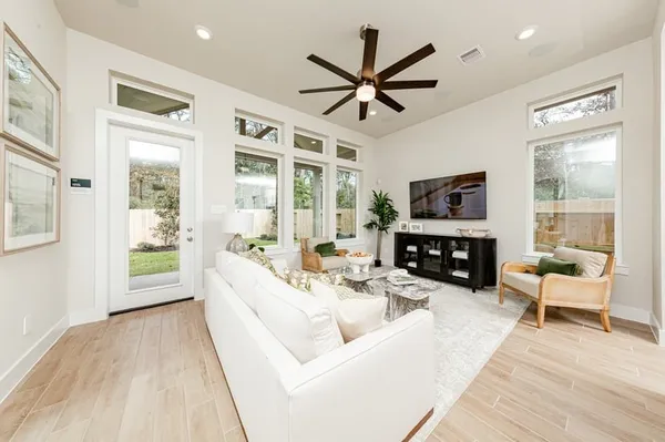 a living room with furniture a ceiling fan a flat screen tv and a large window