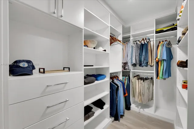 a view of walk in closet with clothes and shoes