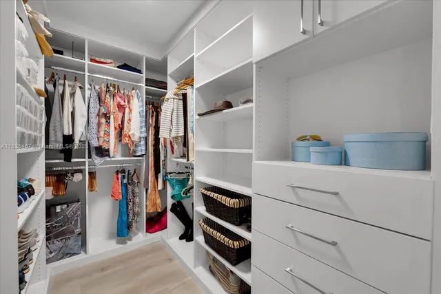 a view of walk in closet with clothes and shoes