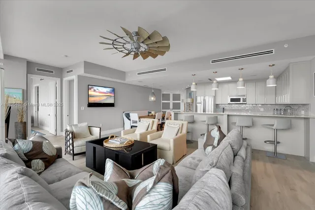 a living room with furniture kitchen view and a wooden floor
