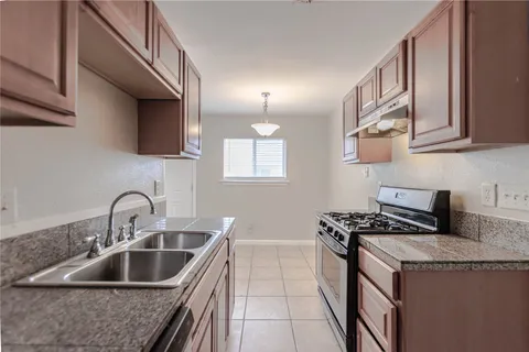 a kitchen with granite countertop a sink stove and cabinets