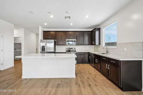 a large kitchen with stainless steel appliances granite countertop a stove a sink dishwasher and a refrigerator with wooden floor