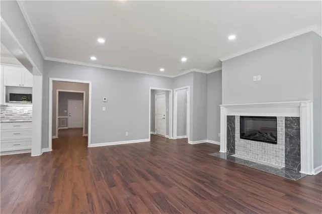 a view of an empty room with wooden floor fireplace and a window