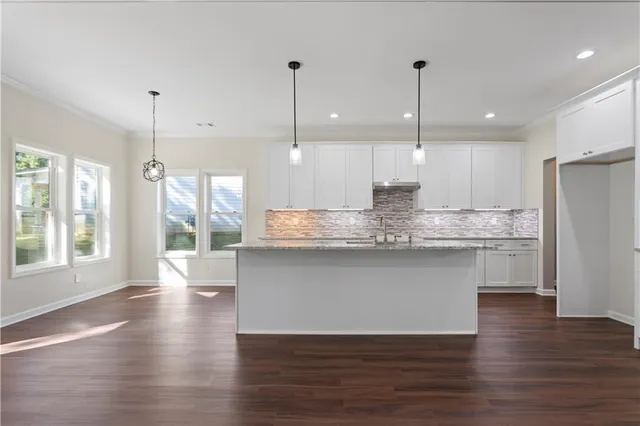 a view of a kitchen with a refrigerator a large window and wooden floor