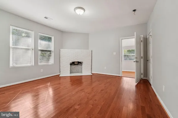 a view of an empty room with window and wooden floor