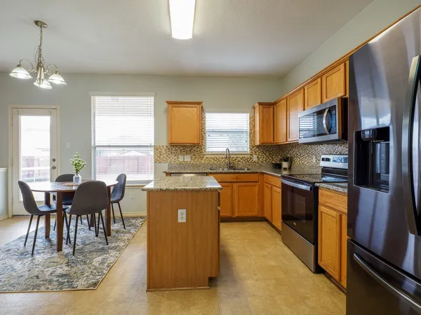 a kitchen with stainless steel appliances granite countertop a stove top oven a sink dishwasher a dining table and chairs with wooden floor