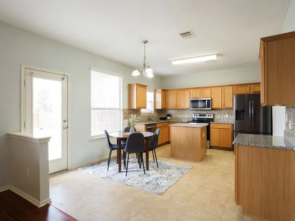 a kitchen with kitchen island granite countertop a refrigerator a stove top oven a sink dishwasher and white cabinets with wooden floor