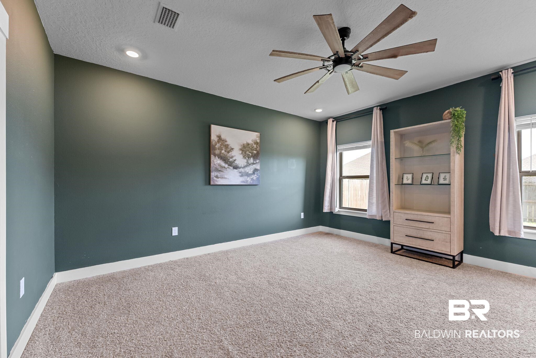 16607 Prado Loop Loxley, AL 36551 - Photo 29 of 46 Carpeted room featuring dark green walls, two windows with blinds and curtains, recessed lighting, and a multi-blade ceiling fan with integrated light