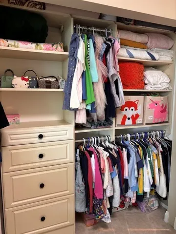 a view of walk in closet with clothes and shoes