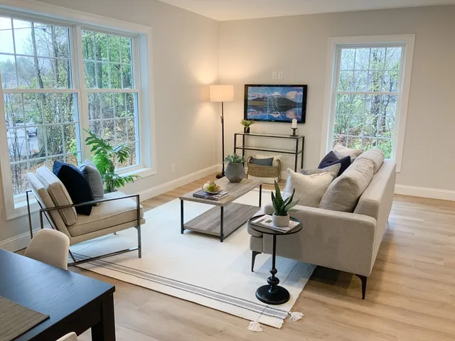 a living room with furniture a lamp wooden floor and a large window