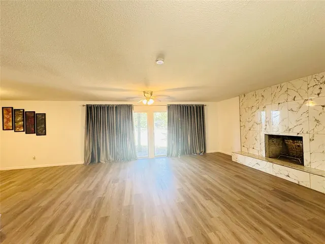 a view of an empty room with wooden floor and a fireplace