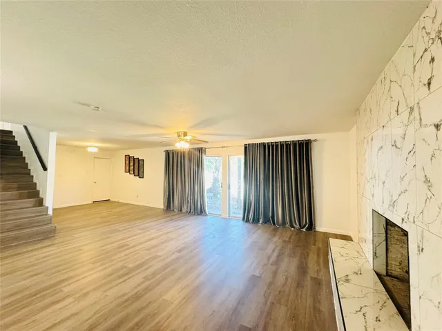 a view of an empty room with wooden floor and a fireplace