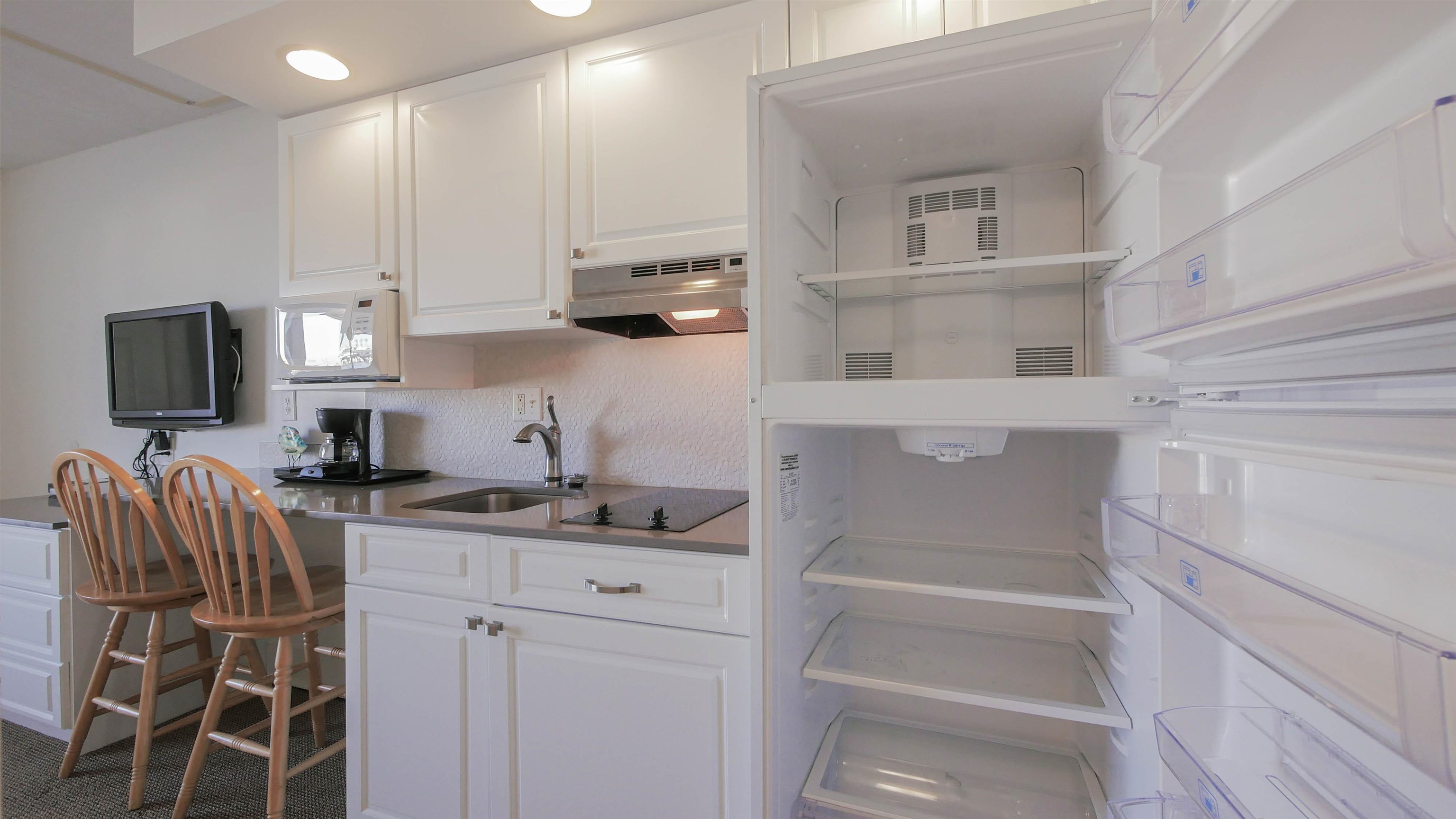 7800 Dune Drive, Unit 209 Avalon, NJ 08202 - Photo 19 of 21 a kitchen with stainless steel appliances granite countertop a sink and a stove top oven with wooden floor