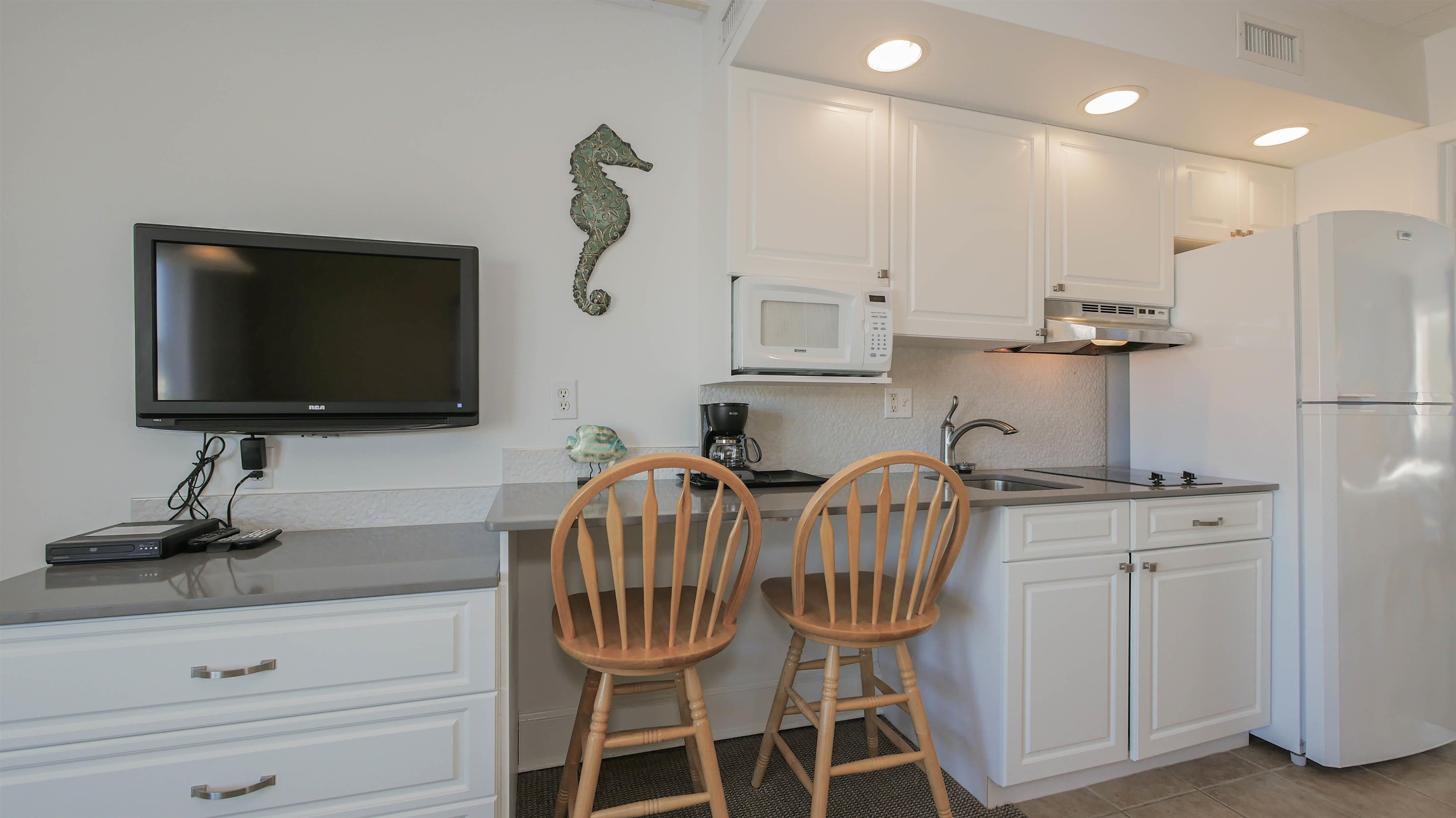 7800 Dune Drive, Unit 209 Avalon, NJ 08202 - Photo 10 of 21 a kitchen with stainless steel appliances a microwave a stove and white cabinets