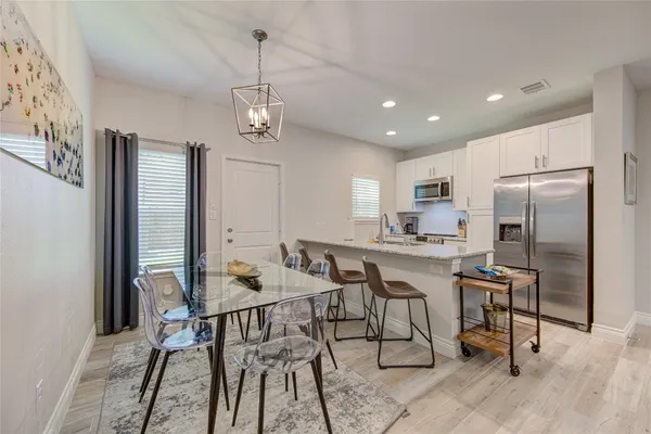 a kitchen with stainless steel appliances granite countertop a dining table chairs refrigerator and cabinets