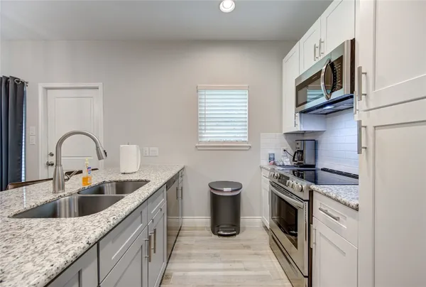 a kitchen with granite countertop a sink stainless steel appliances and cabinets