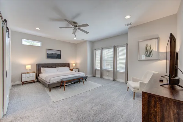 a spacious bedroom with a bed a couch and a large window