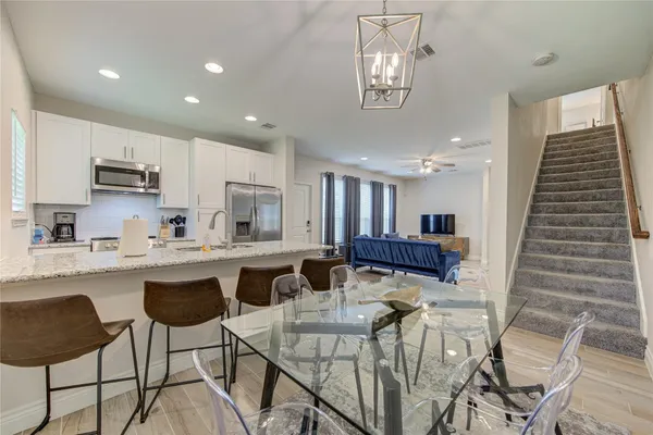 a kitchen with stainless steel appliances kitchen island granite countertop a dining table chairs and sink
