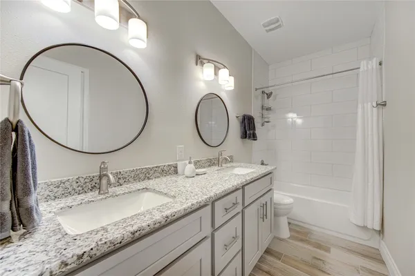 a bathroom with a granite countertop double vanity sink and a mirror