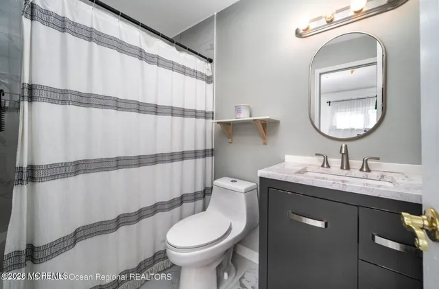 a bathroom with a granite countertop sink toilet a mirror and shower