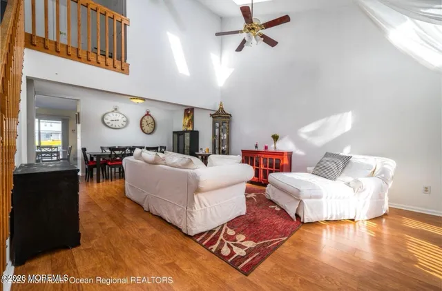 a living room with couches and a dining table with wooden floor