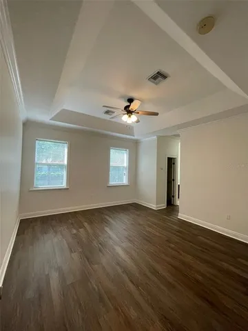 an empty room with wooden floor and windows