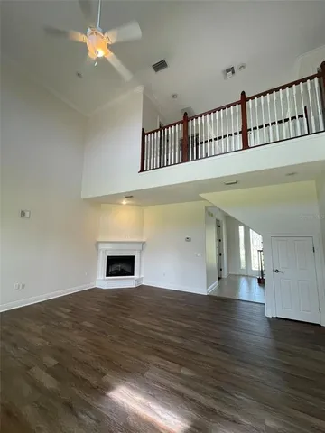 a view of an empty room with wooden floor and a fireplace