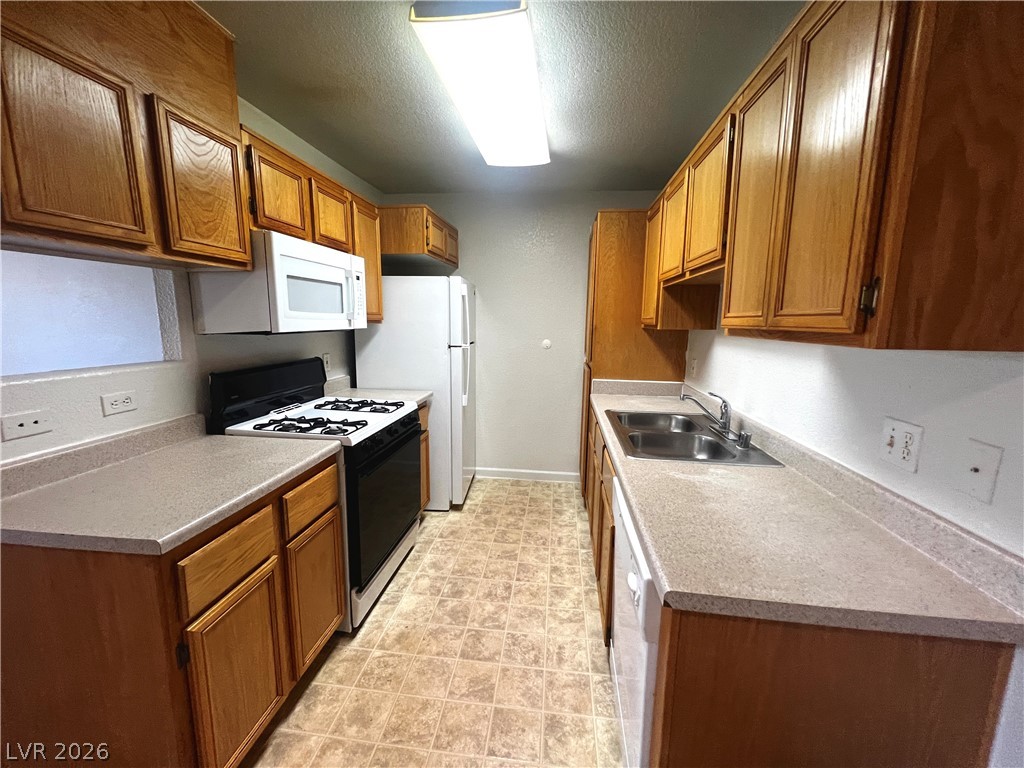 4730 East Craig Road, Unit 2104 Las Vegas, NV 89115 - Photo 7 of 20 A galley-style kitchen with natural wood cabinetry and neutral countertops awaits culinary creativity.