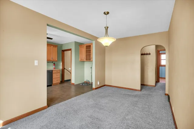 an empty room with chandelier fan and windows