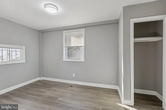 an empty room with wooden floor and windows