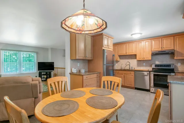 a kitchen with stainless steel appliances a dining table chairs microwave and sink