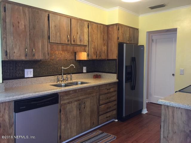 4773 Myrtlewood Road Jacksonville, FL 32210 - Photo 5 of 12 a kitchen with stainless steel appliances granite countertop a sink a refrigerator and wooden cabinets