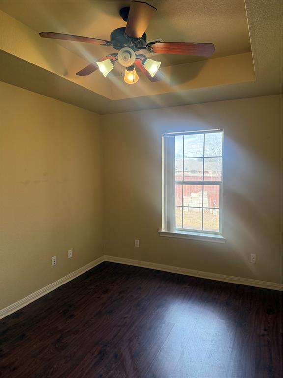 2524 Riders Way Woodway, TX 76712 - Photo 23 of 35 Empty room with a raised ceiling, ceiling fan, and dark wood-style floors
