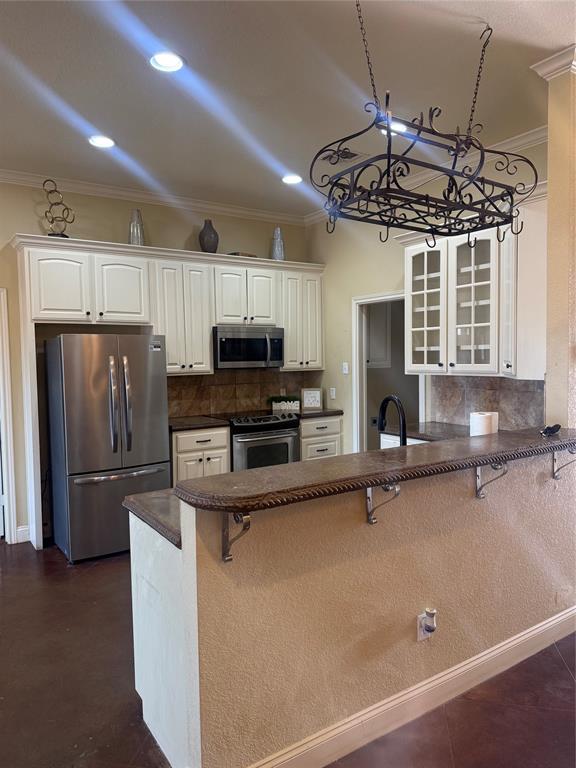2524 Riders Way Woodway, TX 76712 - Photo 3 of 35 Kitchen with a kitchen bar, stainless steel appliances, white cabinetry, and crown molding