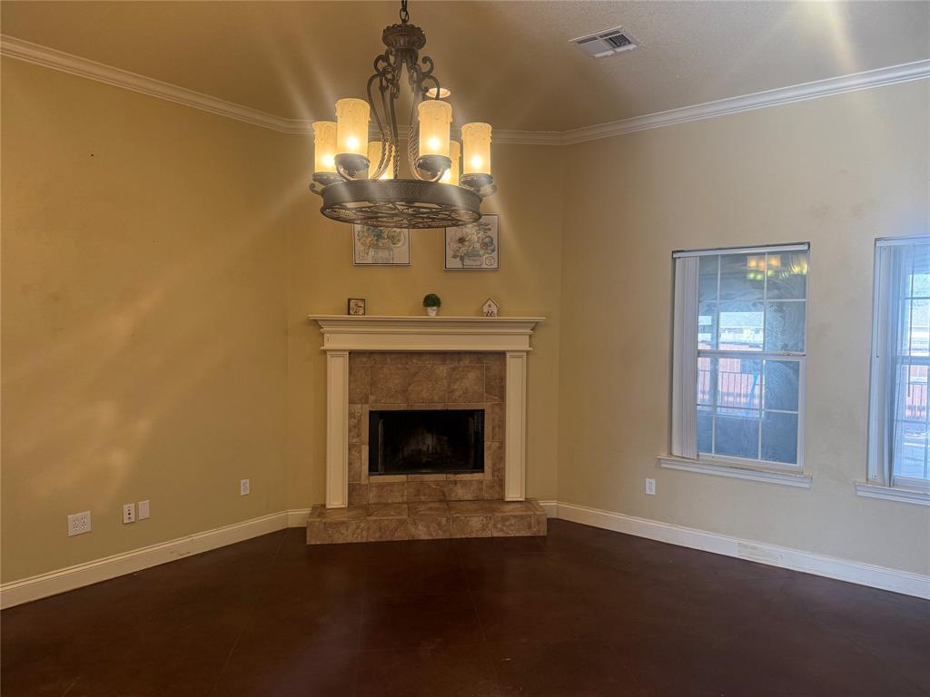 2524 Riders Way Woodway, TX 76712 - Photo 6 of 35 Unfurnished living room featuring crown molding, a fireplace with raised hearth, and a chandelier