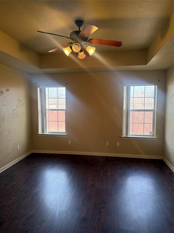 2524 Riders Way Woodway, TX 76712 - Photo 7 of 35 Unfurnished room featuring a textured ceiling, a tray ceiling, a ceiling fan, and dark wood-style floors