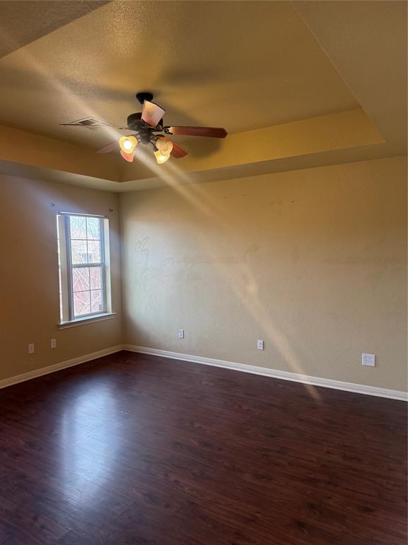 2524 Riders Way Woodway, TX 76712 - Photo 8 of 35 Unfurnished room featuring a raised ceiling, dark wood finished floors, and a ceiling fan