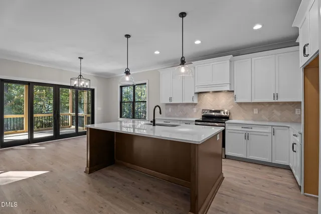 a kitchen with stainless steel appliances granite countertop a sink a stove and a wooden floors
