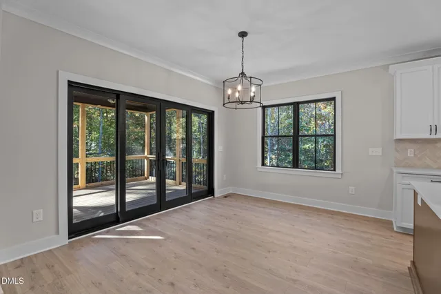 a view of an empty room with window and chandelier