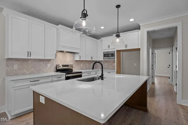 a kitchen with kitchen island a stove a sink a refrigerator and cabinets