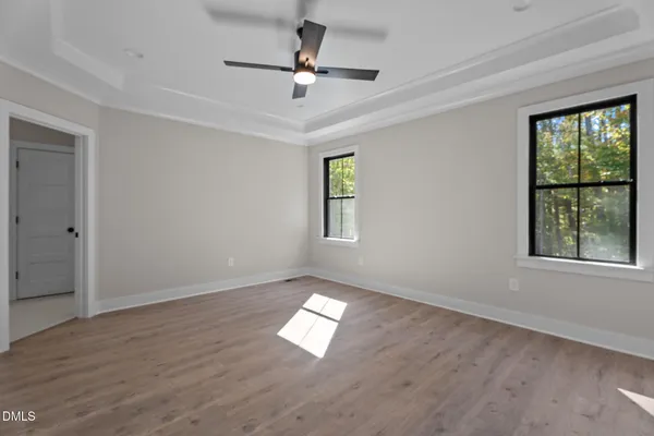 an empty room with wooden floor ceiling fan and windows