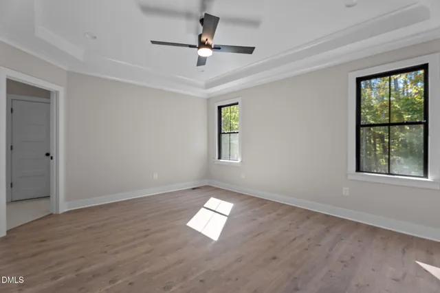 an empty room with wooden floor ceiling fan and windows